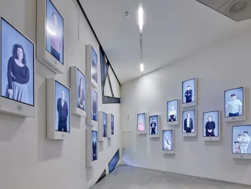 Wand mit mehreren Bildschirmen, auf denen Personen sind.