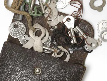 Börse aus braunem Leder und 31 ausgebreitete Schlüssel.