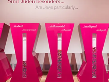 Fünf Säulen zum Einwerfen von Jetons mit den Aufschriften: »geschäftstüchig?«. »tierlieb?«, »einflussreich?«, »intelligent?«, »schön?«.