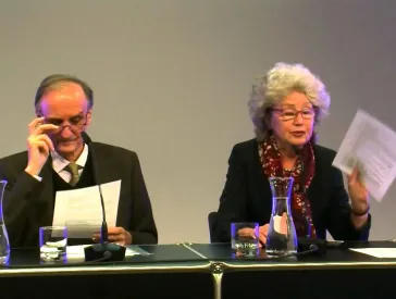 Ein Mann und eine Frau an einem Tisch halten einen Vortrag.