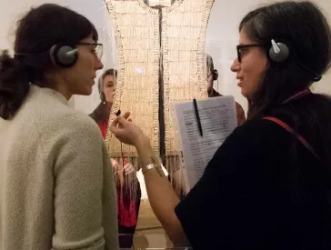 Zwei Frauen unterhalten sich vor einem Kunstwerk in der Ausstellung.