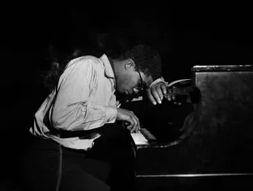 Ein Klavierspieler, mit gesenktem Kopf, der auf seiner Hand ruht.