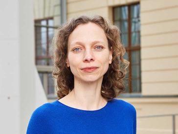 Portrait photo of a smiling woman wearing a bright blue jumper. She looks directly into the camera.