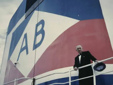 Ein Mann in Anzug steht an einer Rehling.