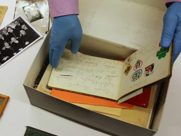 Hände greifen in einen Karton mit Briefen.