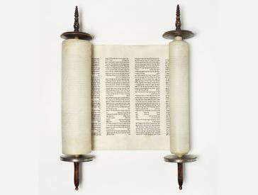 A Torah scroll is unrolled to show two columns of Hebrew text.
