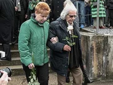 Horst Selbiger with Petra Pau at a memorial service, holding a white rose.
