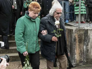Horst Selbiger mit Petra Pau bei einer Gedenkveranstaltung, in der Hand eine wei&szlig;e Rose.