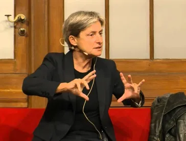 Judith Butler sitzt auf einem roten Sofa