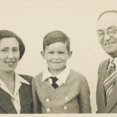 B-W image. Heavily yellowed. A woman, a child and a man in formal dress look friendly into the camera. 