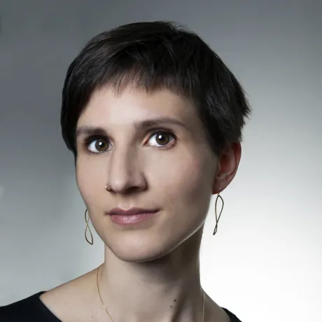 Eine Frau mit kurzen Haaren schaut freundlich in die Kamera. Sie tr&auml;gt Ohrringe und eine Kette.