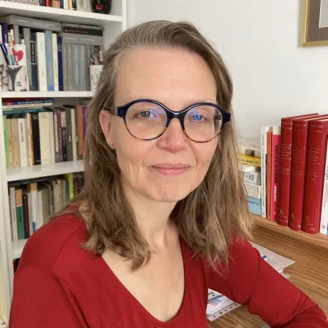 A woman wearing glasses looks friendly at the camera.