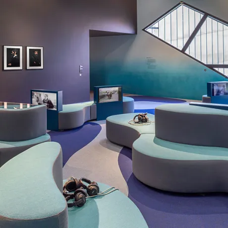 Room with color gradient from purple to turquoise blue, sofas, headphones, screens