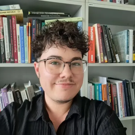 Eine Person mit Brille schaut freundlich in die Kamera.