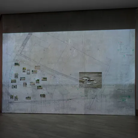 Blick auf eine Ausstellungswand mit großem Stadtplanausschnitt und darauf geklebte Fotos.