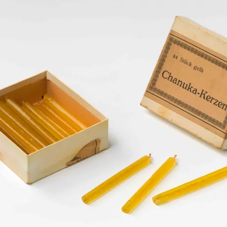 Ein alter geöffneter Karton mit gelben Kerzen.