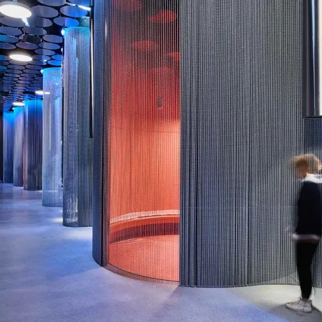 Room view with round seat bunk and person under a hanging sound tube