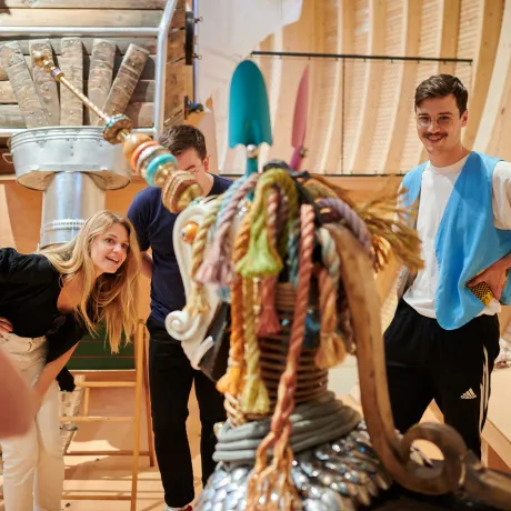 Drei Erwachsene begutachten eine Tier-Skulptur.