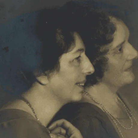 Old picture of two women in profile leaning against each other.