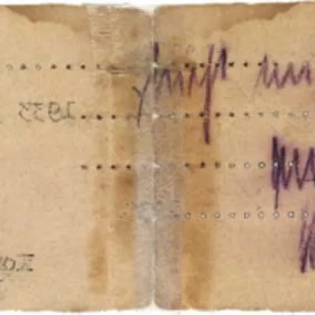 R&uuml;ckseite eines vergilbten Zettels in extremem Querformat. Einige Buchstaben des Schreibmaschinentextes der Vorderseite sind als spiegelverkehrter Abdruck sichtbar, au&szlig;erdem eine handschriftliche Notiz