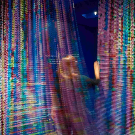 Colorful curtain in motion through which a person passes.