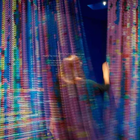 Colorful curtain in motion through which a person passes.