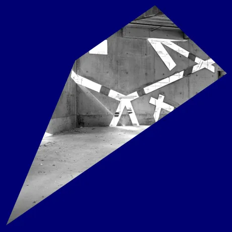 Blaues Passpartout um ein schwarz-wei&szlig;-Foto eines noch im Bau befindlichen, leeren Raums, in dessen Betonw&auml;nden sehr schr&auml;ge Fenster sind, durch die Licht einf&auml;llt.