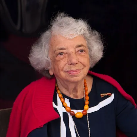 Frau (Margot Friedländer) mit weißem Haar auffälliger Bernsteinkette schaut freundlich in die Kamera.