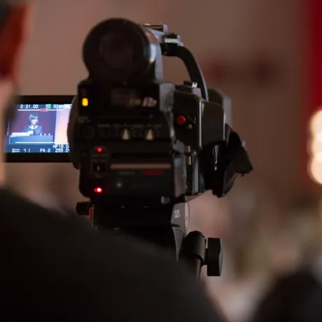 Filmkamera aus der Perspektive  eines Kameramannes, der eine Veranstaltung aufzeichnet.