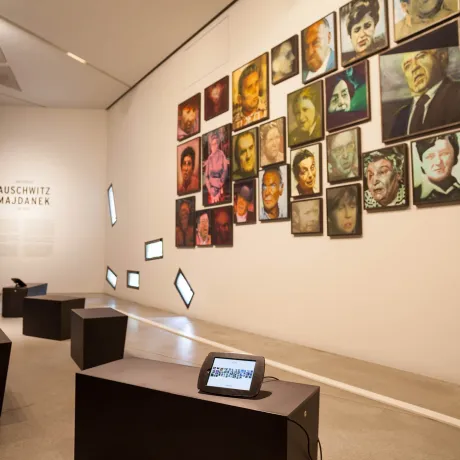 Multi-colored painted portraits of men and women line the wall facing black chairs equiped with tablets