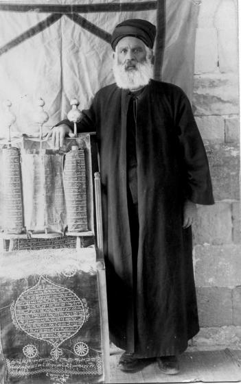 Schwarz-weiß-Foto eines bärtigen Mannes, der seine Hand über eine Tora hält