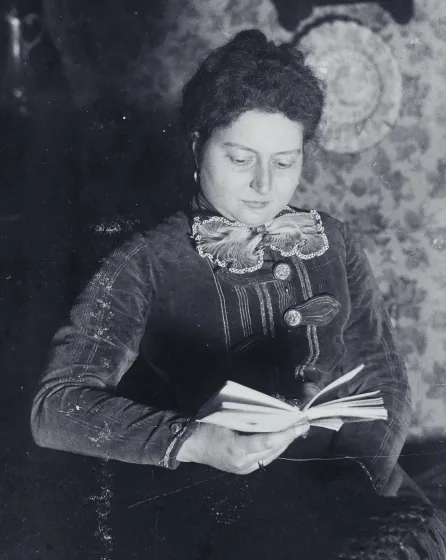 Porträt einer Frau, die ein Buch in der Hand hält und zu lesen scheint.