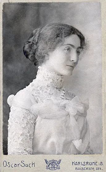  Lateral black and white photograph of a woman. She is wearing a lace dress.