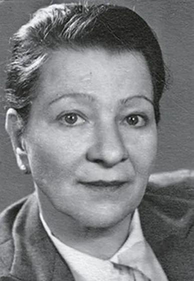 The black and white photo shows a woman looking directly towards the camera. Her hair is short.
