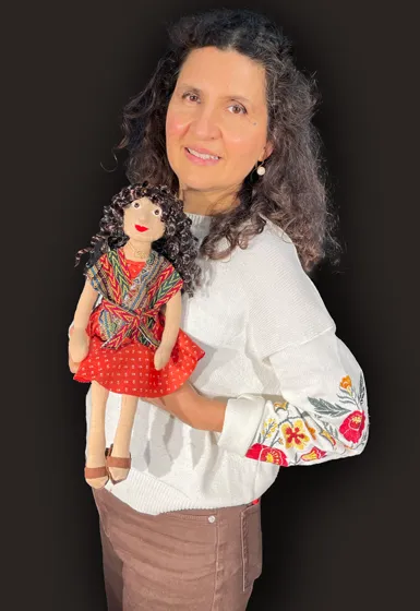 A woman with long black hair is holding a puppet in her hands.