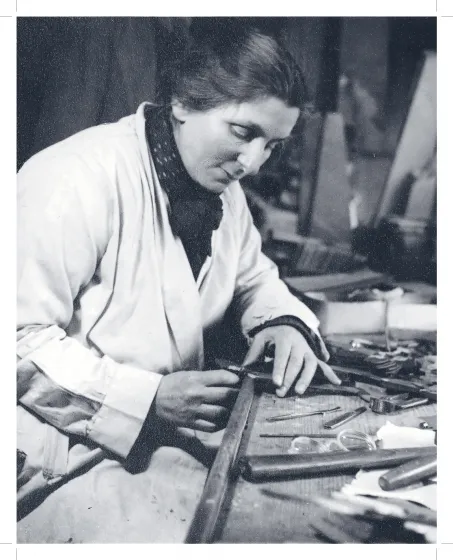 Historische Aufnahme einer vornübergebeugt an einem Werktisch arbeitende Frau. 
