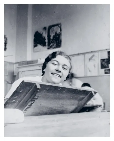 Fotografie einer Frau, die hinter einem Holztisch sitzt. 