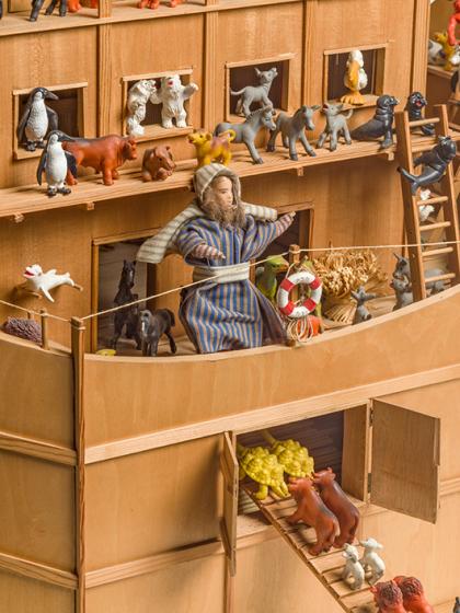 Close-up of the wooden ark with toy animals; a bearded figure in a striped robe stands in the center.