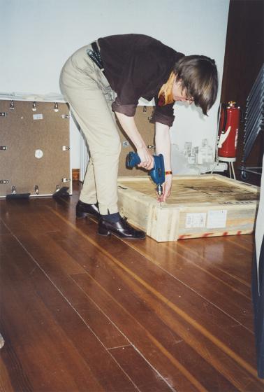 Eine Frau schraubt die Holzverpackung eines großen Pakets aus