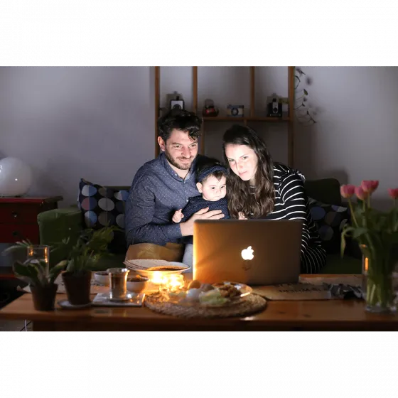 A man, a child and a woman sitting in front of a laptop