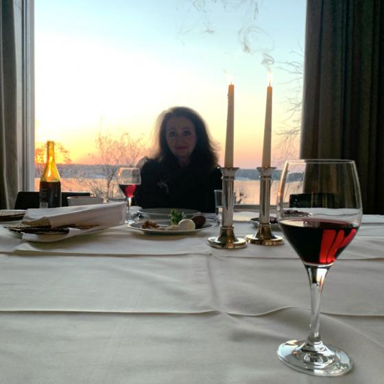 A woman is sitting at a set table with two burning candles.