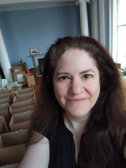 Selfie of Michal S. Friedlander in a room with boxes on the floor and blue wall paint