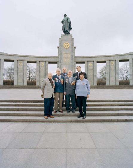  Old people stand on the stairs in front of a monument