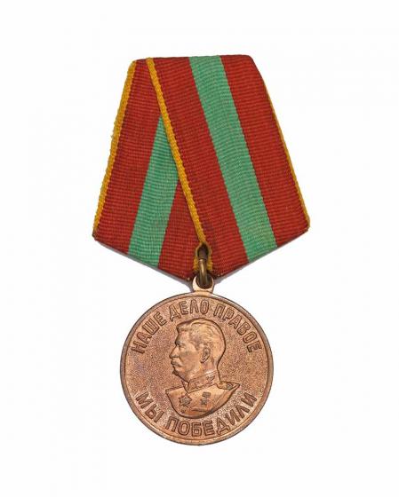 Bronzefarbene Medaille mit einem Reliefbild Stalins und kyrillischer Schrift an einem rot-grün gestreiften Band