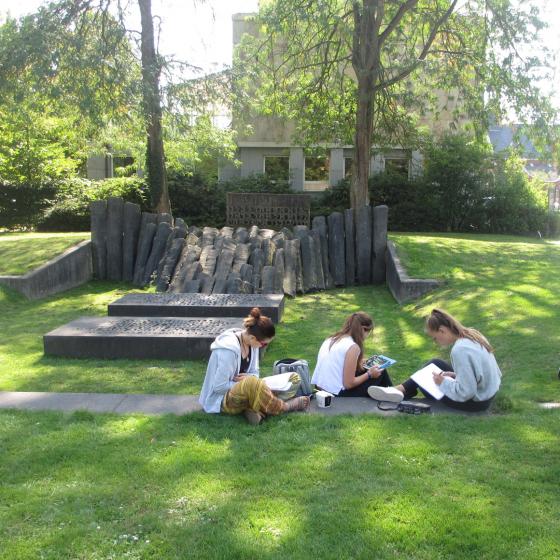 Jugendliche im Park auf einer Wiese mit Schreibutensilien