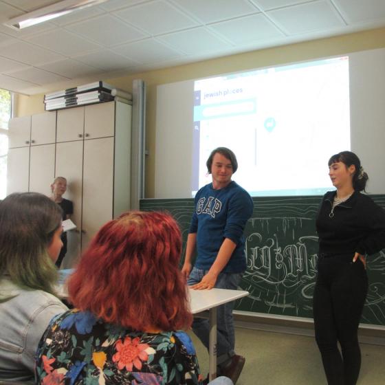 Students giving a presentation in front of an electronic whiteboard