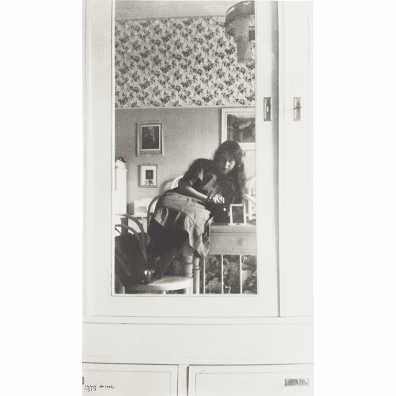 Teenage girl in a mirror attached to the door of a light cabinet