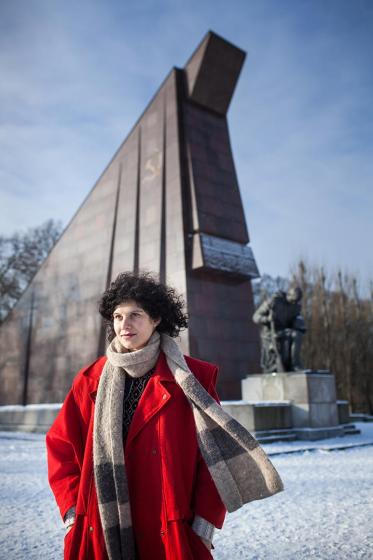 Photo: a woman in a red coat in front of the Soviet War Memorial in Treptower Park in the snow
