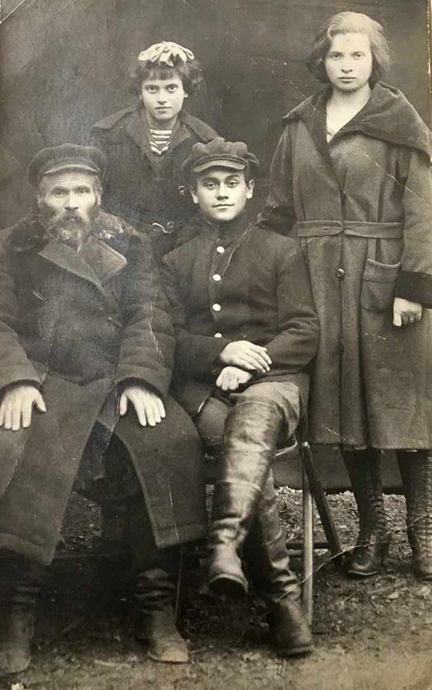 Schwarz-weiß-Gruppenfoto: Ein bärtiger Mann und ein junge sitzend, ein jüngeres und ein älteres Mädchen dahinter stehend, alle in Mänteln