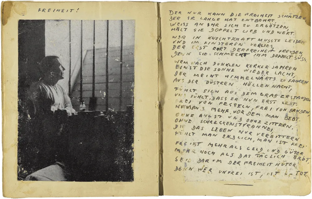 Handschriftlich verfasste Doppelseite in Druckbuchstaben mit eingeklebtem Foto eines Mann, der durch die Gitter seiner Zelle schaut, und dem Titel: „Freiheit“.